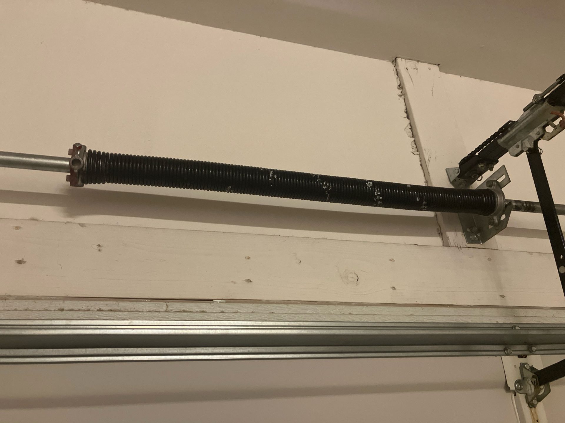 Garage door torsion spring – close-up view of a broken or worn spring in need of repair