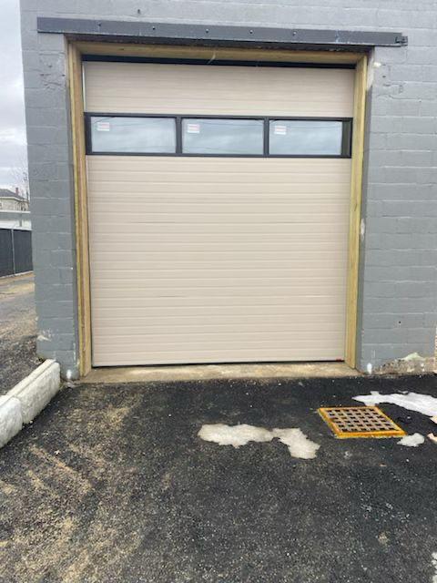 Commercial garage door installed on gray industrial structure – final result